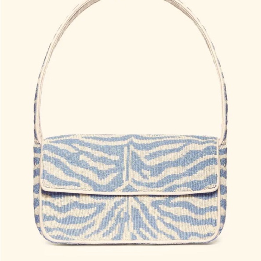 Tommy Bag is a hand-beaded shoulder bag with leather piping.